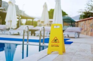 Cartel de advertencia de suelo mojado junto a una piscina de hotel