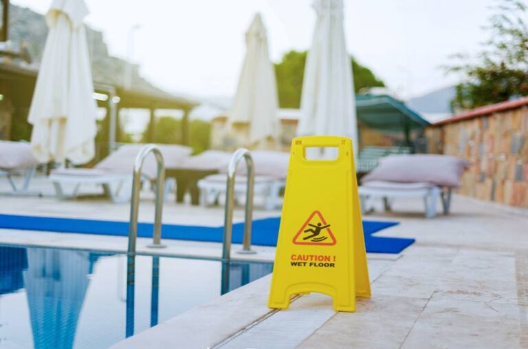Cartel de advertencia de suelo mojado junto a una piscina de hotel